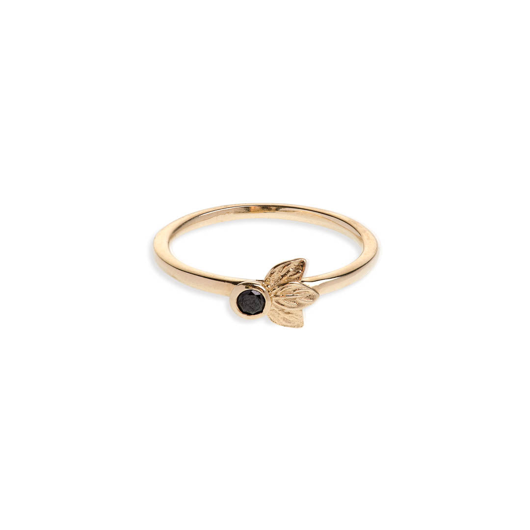 Black diamond in a classic tube setting on a yellow gold ring with three leaf details