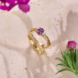 Two gold rings; one with a purple sapphire  and natural diamonds, and the other with natural diamonds on a textured surface with flowers.